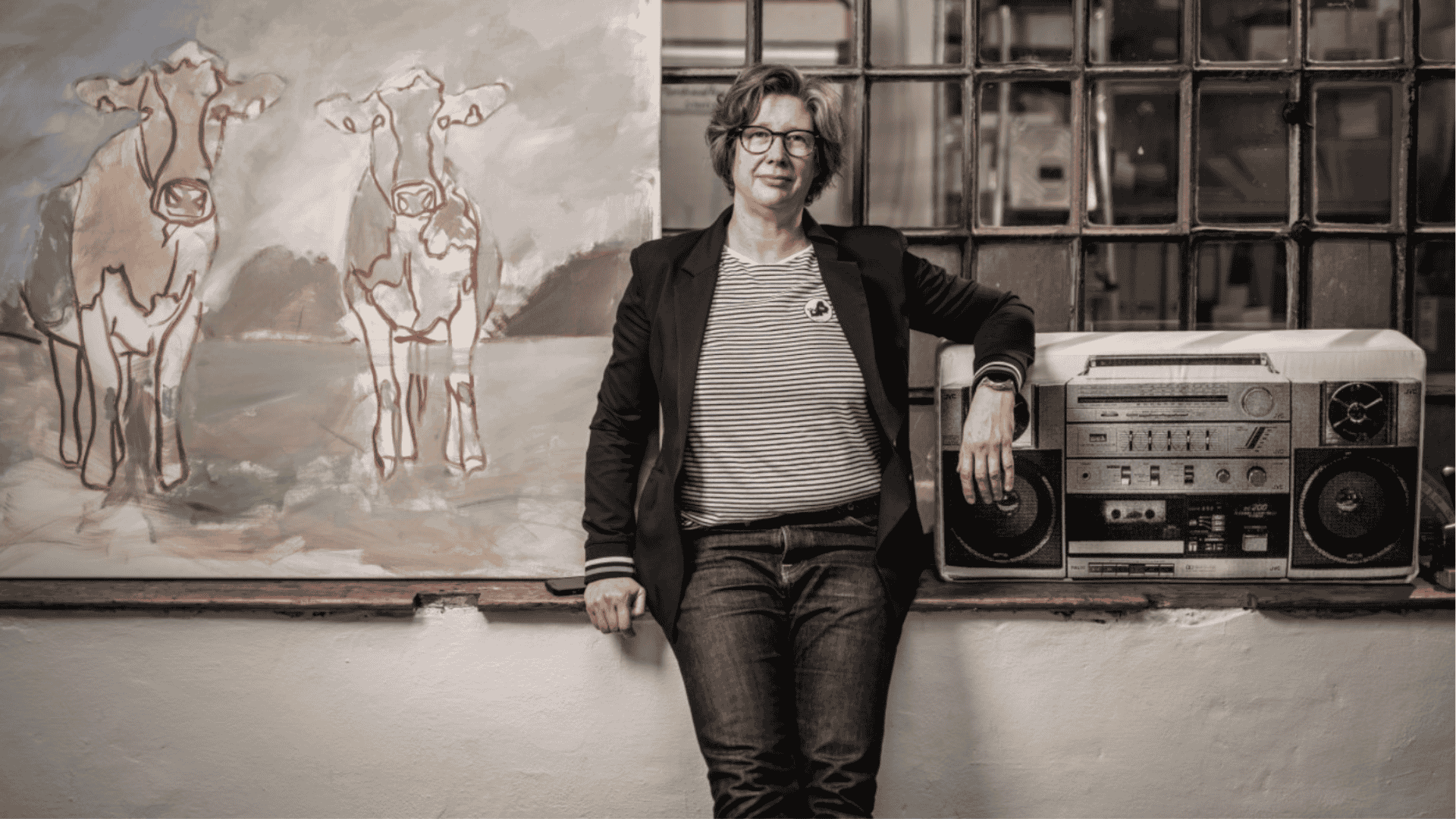 Maren Martschenko steht und sitzt leicht angelehnt an einem Absatz. Neben ihr ein Ghettoblaster und hinter ihr hängt eine Weltkarte.