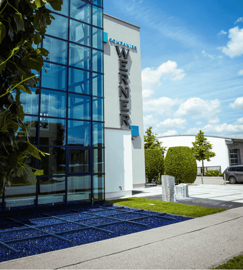 Das Gebäude der WERNER Companies bei blauem Himmel und ein paar Bäumen drumherum.